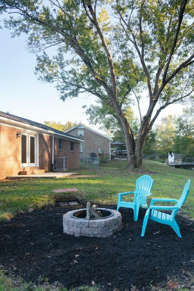 view of yard with french doors, a fire pit, and central AC