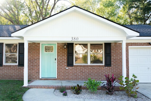 ranch-style house with brick siding, an attached garage, and roof with shingles