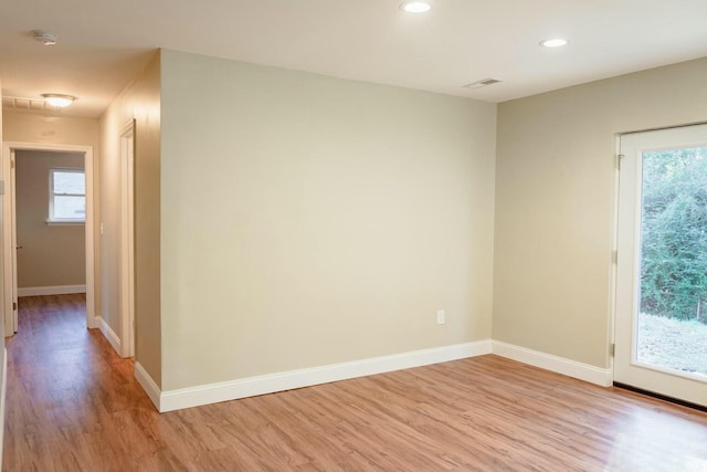 spare room featuring baseboards, plenty of natural light, and light wood finished floors