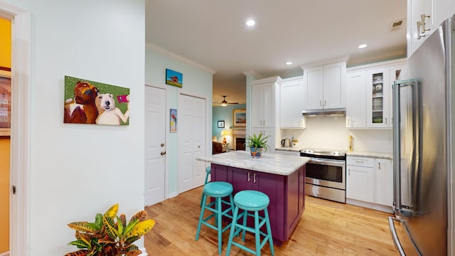 kitchen featuring a center island, stainless steel appliances, light wood-style flooring, ornamental molding, and under cabinet range hood