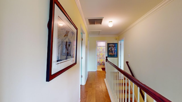 hallway with light wood finished floors, visible vents, ornamental molding, an upstairs landing, and baseboards