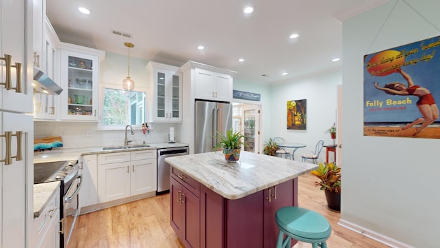 kitchen with a sink, visible vents, appliances with stainless steel finishes, decorative backsplash, and light wood finished floors