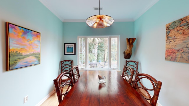 dining room featuring baseboards, visible vents, crown molding, and wood finished floors