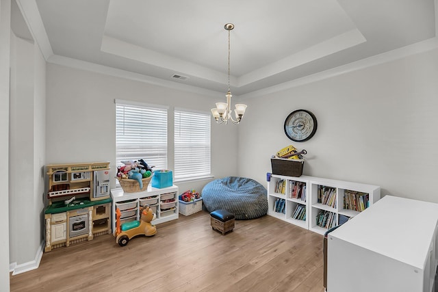 game room featuring an inviting chandelier, a tray ceiling, visible vents, and light wood-style floors
