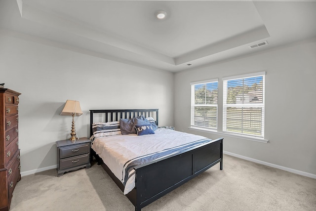 bedroom featuring a raised ceiling, baseboards, visible vents, and light colored carpet