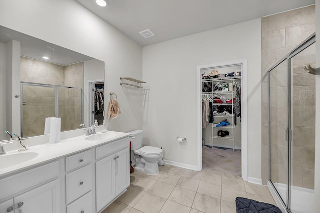 full bathroom featuring double vanity, a shower stall, tile patterned floors, and a sink
