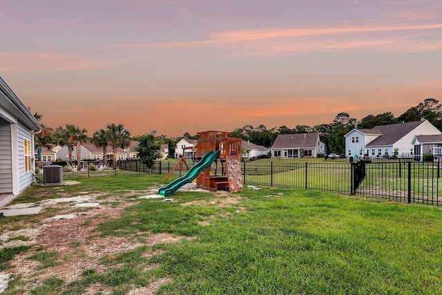 view of yard with a residential view, a fenced backyard, central AC, and a playground
