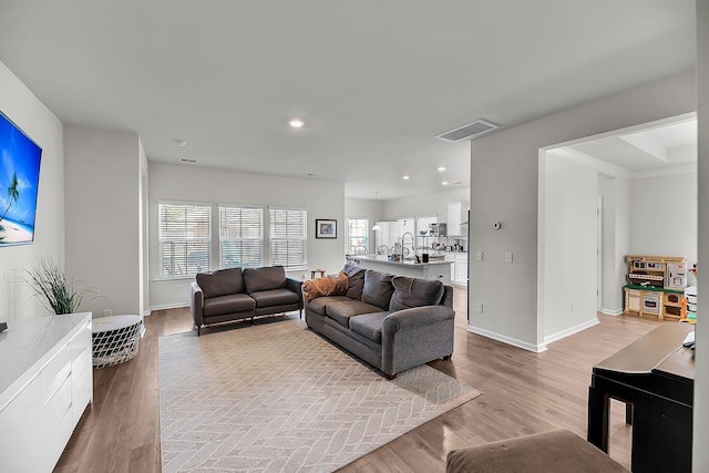 living area with recessed lighting, visible vents, light wood finished floors, and baseboards