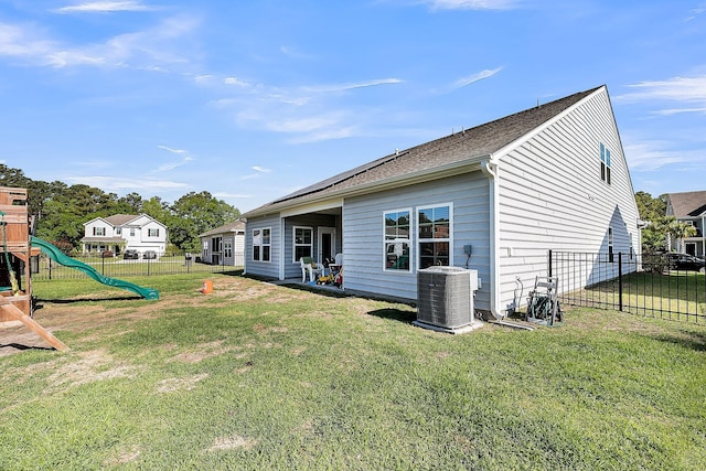 back of house with cooling unit, a yard, a fenced backyard, and a playground