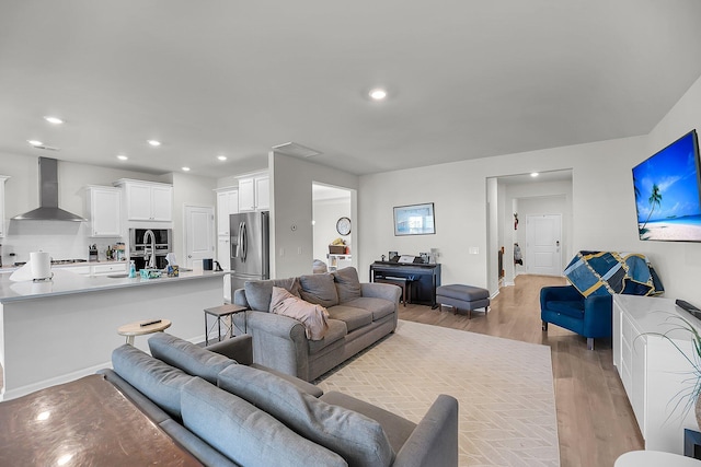 living room featuring visible vents, baseboards, recessed lighting, and light wood-style floors