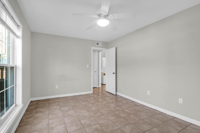 unfurnished room with a ceiling fan, visible vents, and baseboards