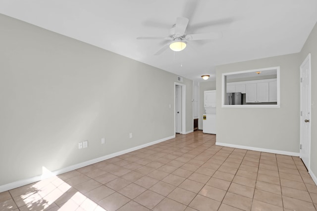 empty room with baseboards, a ceiling fan, and light tile patterned flooring