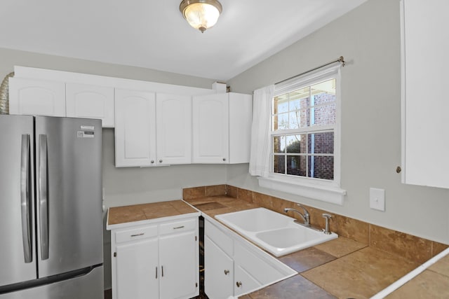 kitchen with freestanding refrigerator, white cabinets, and a sink