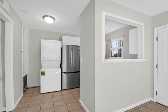 kitchen featuring visible vents, white cabinets, stacked washer / dryer, freestanding refrigerator, and light tile patterned flooring