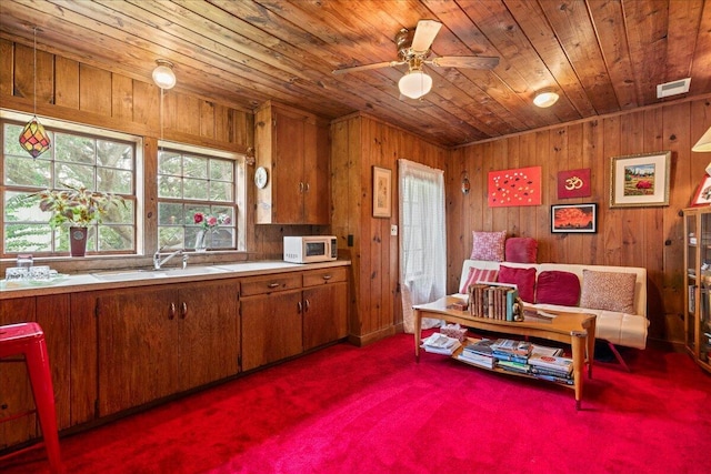 sitting room with dark colored carpet, wooden walls, wooden ceiling, and sink