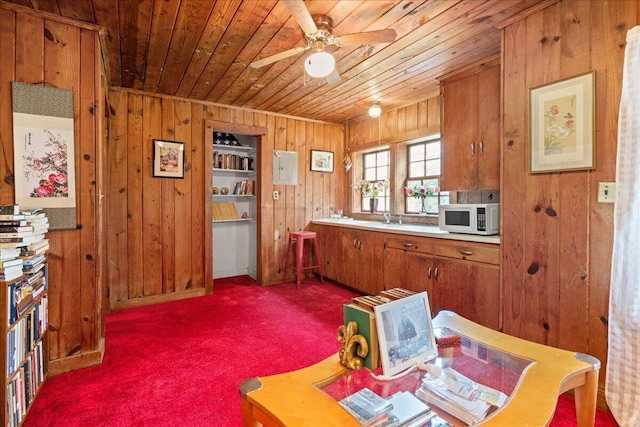 kitchen with dark carpet, wood ceiling, ceiling fan, sink, and wood walls