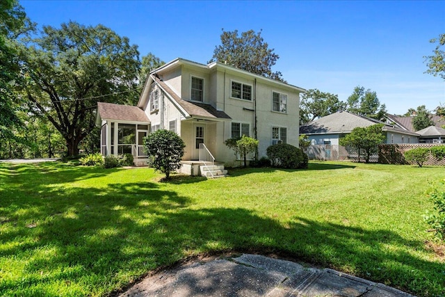 back of property with a sunroom and a yard