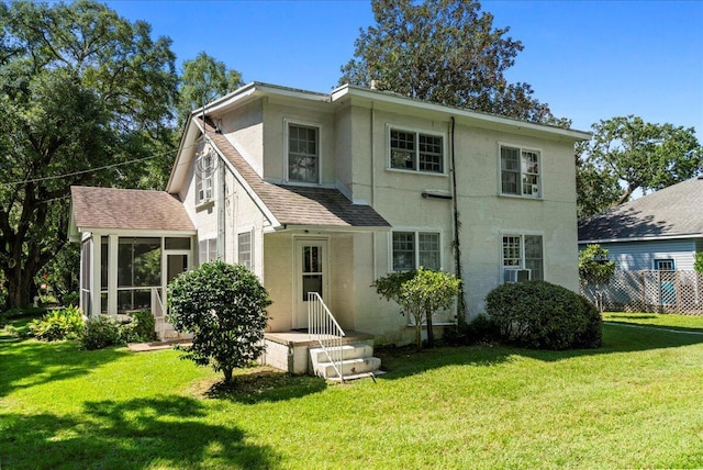 rear view of property featuring a lawn and a sunroom