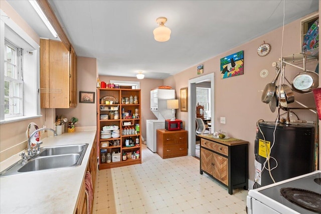 kitchen featuring stove, sink, washer / dryer, and water heater