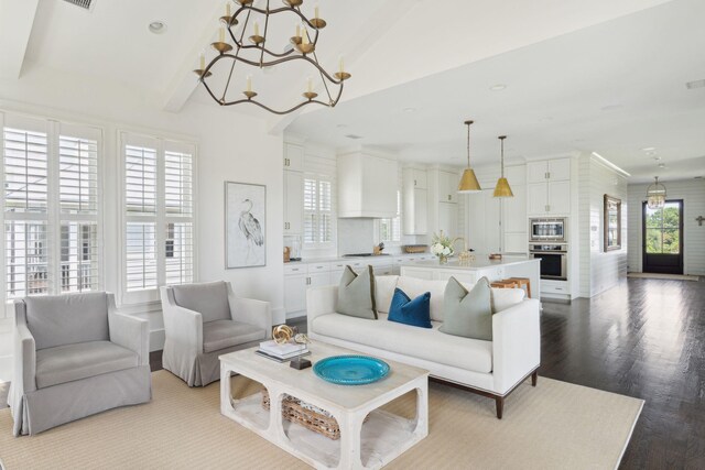 living room with beamed ceiling, a notable chandelier, hardwood / wood-style floors, and a healthy amount of sunlight