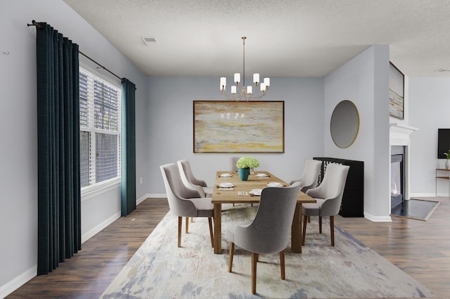 dining space featuring a chandelier, dark wood-type flooring, and a textured ceiling