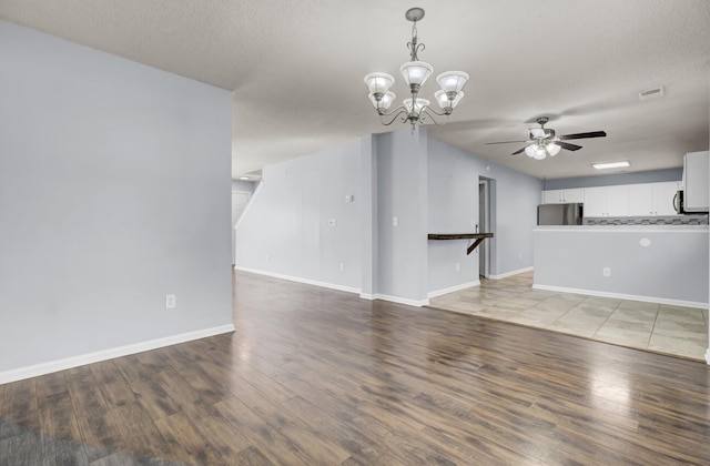 unfurnished living room with hardwood / wood-style flooring, ceiling fan with notable chandelier, and a textured ceiling