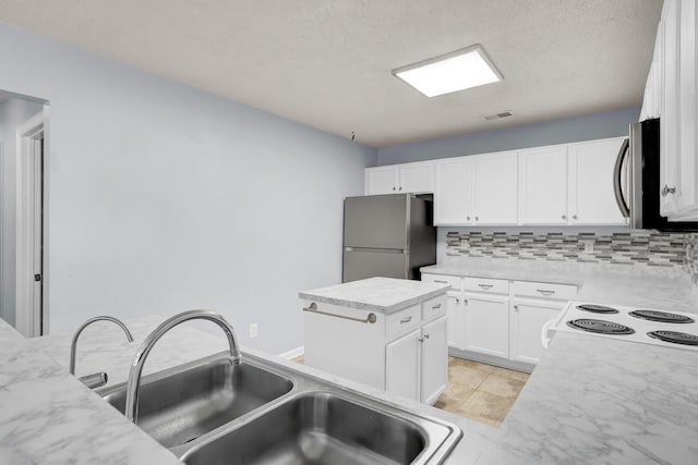 kitchen featuring white cabinets, appliances with stainless steel finishes, a kitchen island, sink, and backsplash