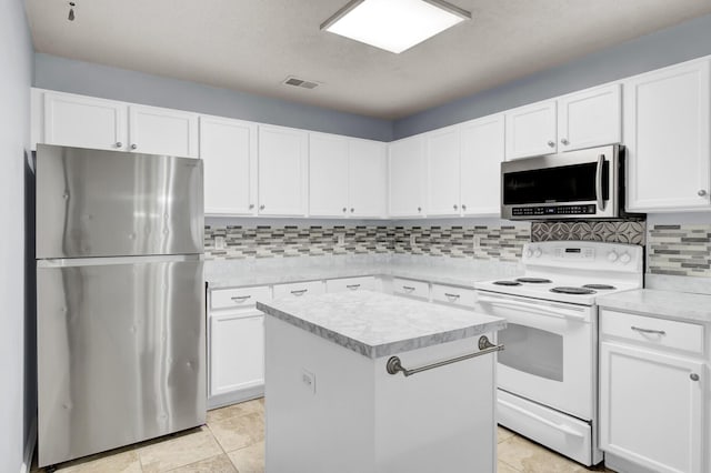 kitchen featuring appliances with stainless steel finishes, backsplash, white cabinetry, light tile patterned floors, and a center island