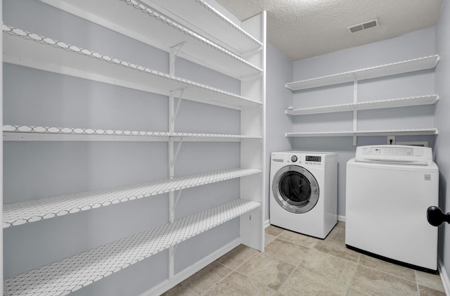 clothes washing area featuring independent washer and dryer and a textured ceiling