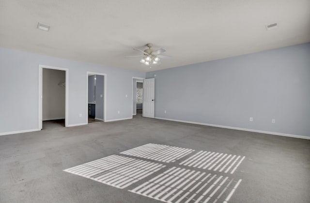 unfurnished bedroom with ceiling fan, carpet, ensuite bath, a walk in closet, and a closet