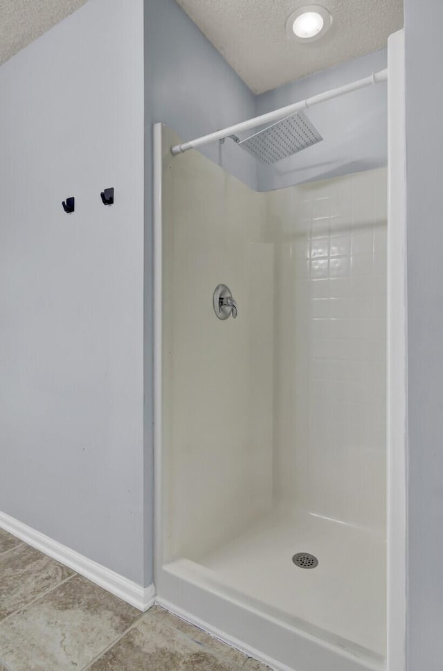 bathroom with a shower and a textured ceiling