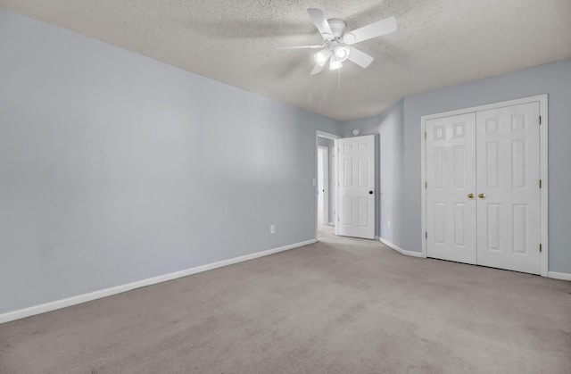 unfurnished bedroom featuring light carpet, a textured ceiling, a closet, and ceiling fan