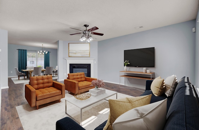 living room featuring ceiling fan with notable chandelier, hardwood / wood-style floors, and a textured ceiling