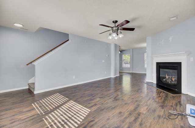 unfurnished living room featuring dark wood-type flooring and ceiling fan