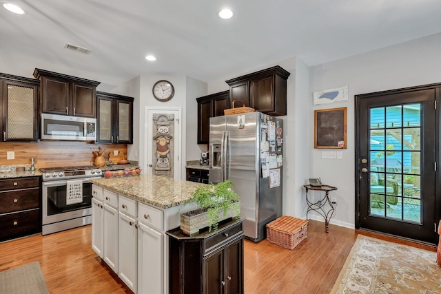 kitchen featuring light stone countertops, appliances with stainless steel finishes, a kitchen island, light hardwood / wood-style flooring, and white cabinetry