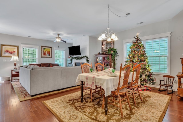 dining room with hardwood / wood-style flooring and ceiling fan with notable chandelier