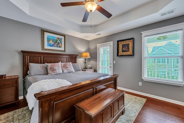 bedroom featuring ceiling fan, a raised ceiling, and dark wood-type flooring