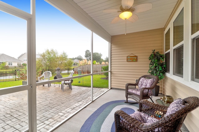 sunroom featuring ceiling fan and a water view