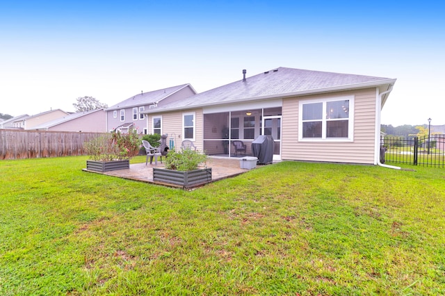 rear view of property featuring a sunroom, a lawn, and a patio area