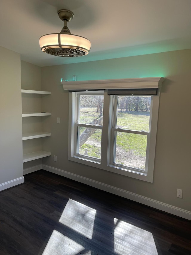 unfurnished dining area featuring dark wood-style flooring and baseboards