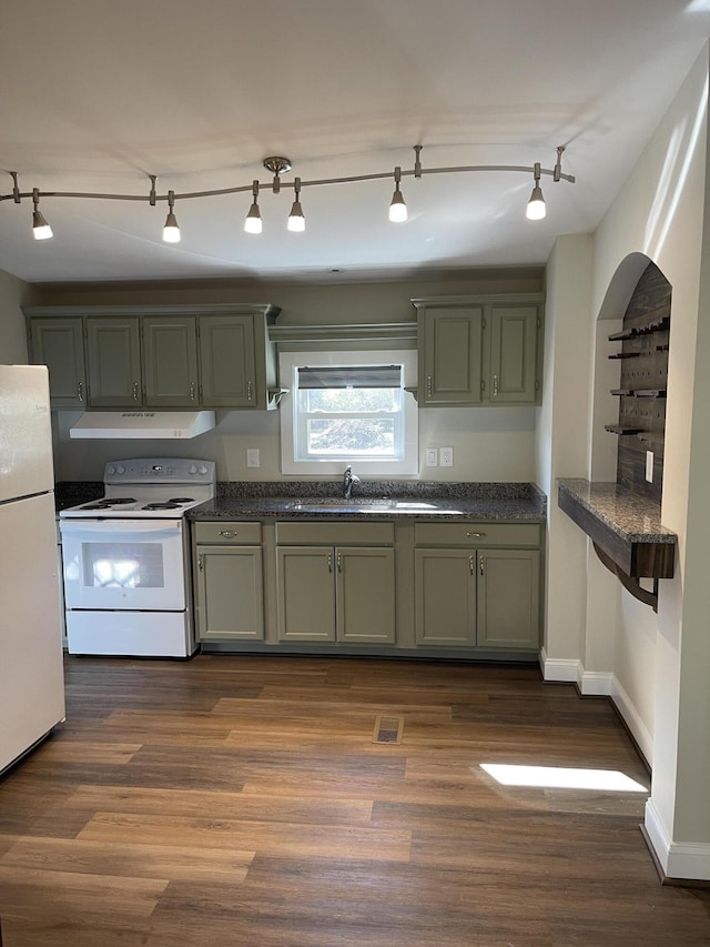 kitchen featuring white appliances, a sink, dark countertops, dark wood finished floors, and green cabinetry