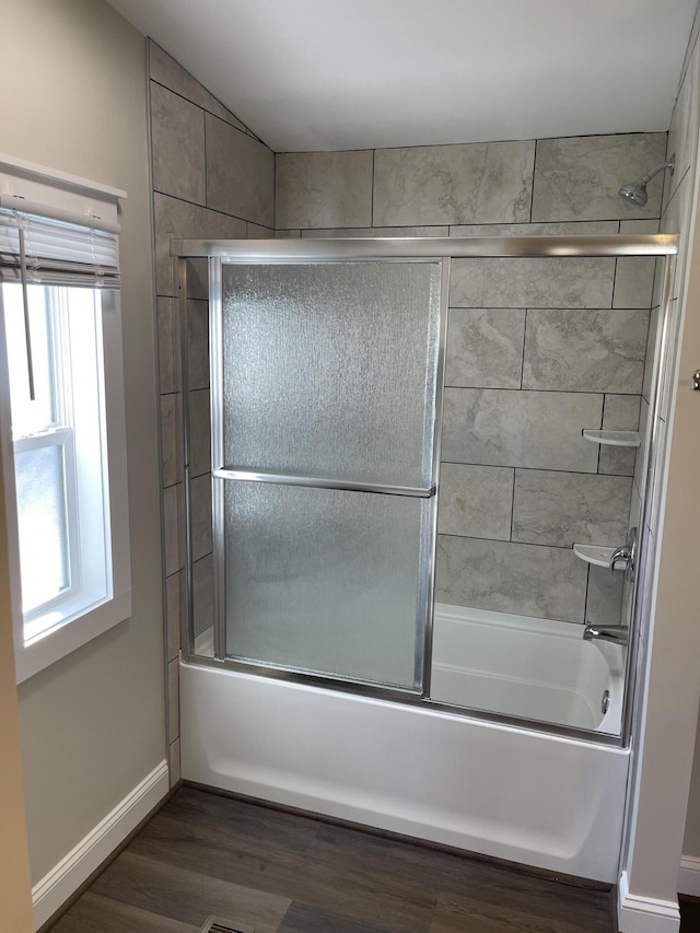 full bath with shower / bath combination with glass door, baseboards, and wood finished floors