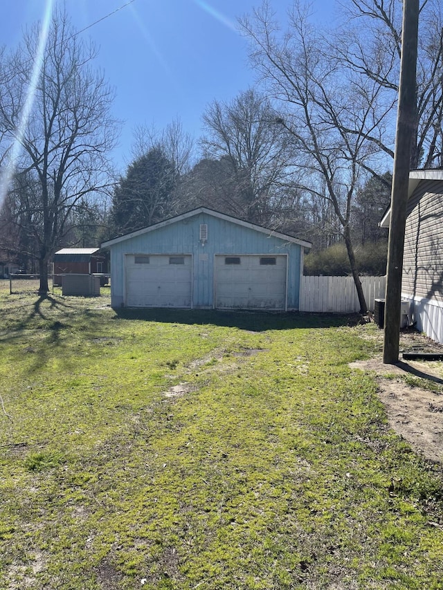 view of yard with a garage, fence, and an outbuilding