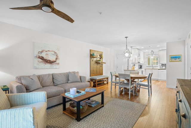 living room featuring ceiling fan, sink, and light wood-type flooring