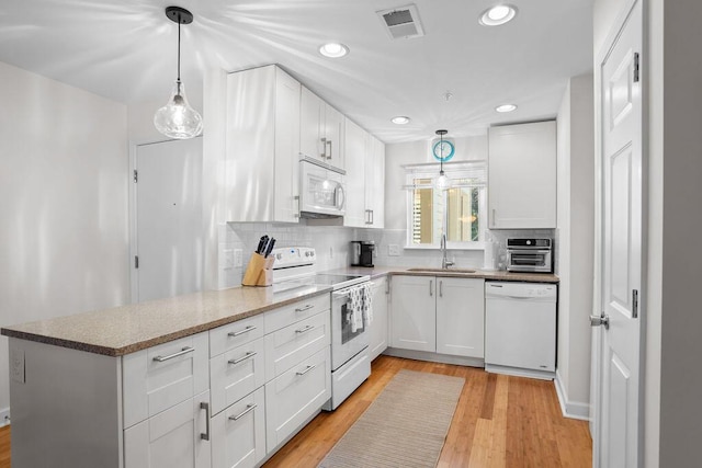 kitchen with white cabinetry, sink, pendant lighting, and white appliances