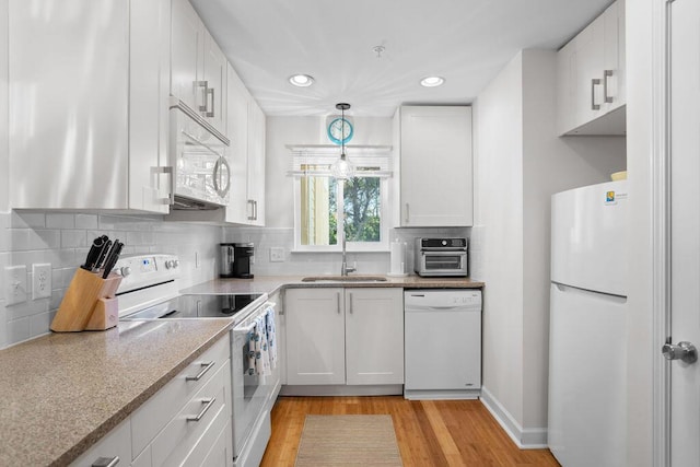 kitchen featuring pendant lighting, white appliances, sink, and white cabinets