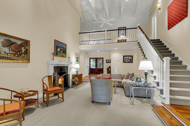 carpeted living room featuring a towering ceiling and ceiling fan