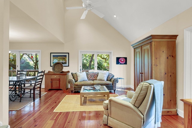 living room with light wood-type flooring, high vaulted ceiling, and ceiling fan