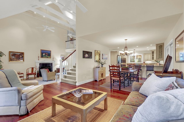 living room featuring ceiling fan with notable chandelier, wood-type flooring, and a towering ceiling