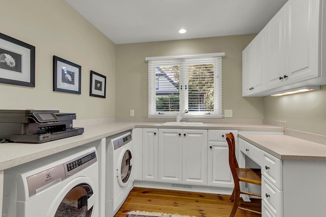 laundry area featuring cabinets, independent washer and dryer, light hardwood / wood-style floors, and sink